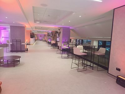 Sala de evento corporativo, sillas altas blancas alrededor de mesas altas