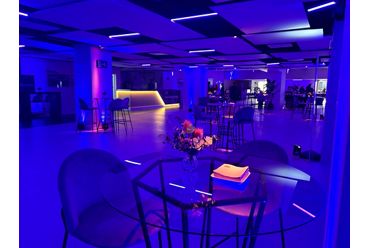 sala con mesas altas con iluminación violeta