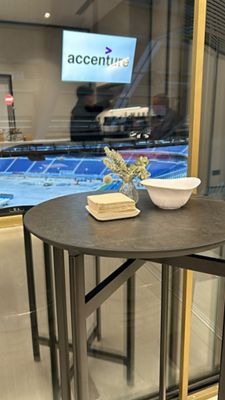 Plano de una mesa alta redonda en sala con ventanal y vista al terreno de juego